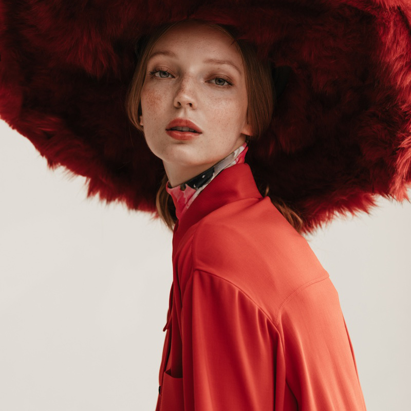 Woman wearing large red fur hat.
