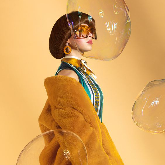 Woman posed sideways, surrounded by large bubbles.